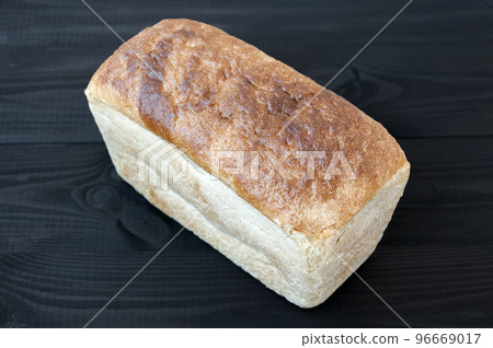 Loaf of wheat bread on white black wooden table. 96669017