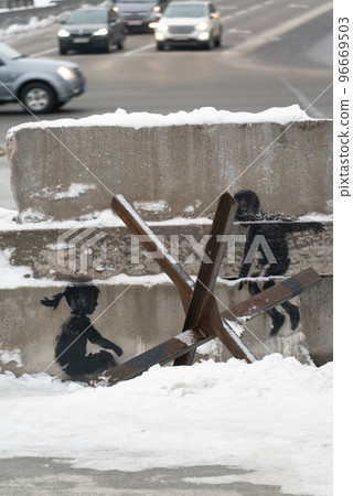 A boy and a girl swing on an anti-tank hedgehog - Banksy graffiti in Kyiv, Ukraine 96669503