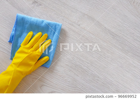 Commercial cleaning company concept. Hand in rubber protective glove with blue microfiber cloth is wiping floor. Copy space. Commercial cleaning company concept. Hand in rubber protective glove with blue microfiber cloth is wiping floor. Copy space. 96669952