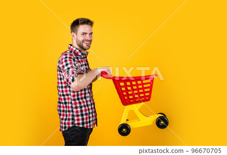 funny man with small shopping cart. weekend on buying products. rejoices successful purchases. spends money unwisely. customer pushing cart. buyer in supermarket. empty toy trolley. man go shopping 96670705