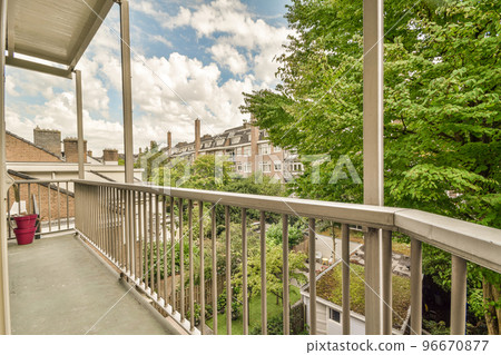 Front view of old brick buildings and cars with bicycles from small balcony with railings 96670877