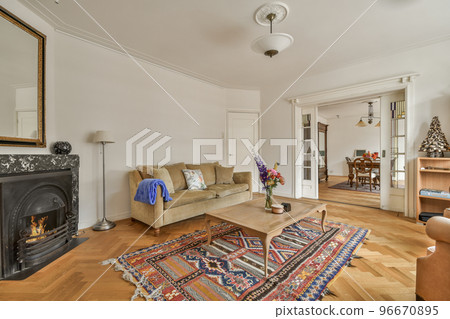 Stylish interior design of living room with light furniture and soft comfy couch and carpet and with TV on cabinet in modern apartment with open kitchen and white walls and column. 96670895