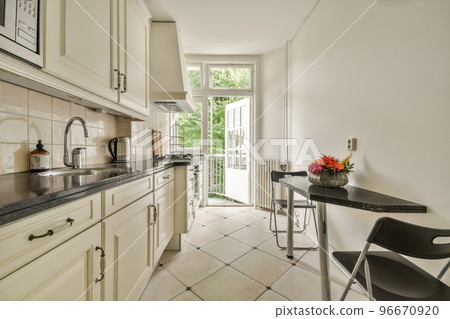 Interior of contemporary kitchen with stylish black cupboards and appliances near dining area in contemporary apartment Interior of contemporary kitchen with stylish black cupboards and appliances near dining area in contemporary apartment 96670920