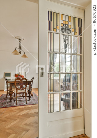 Table and chairs located under glowing lamp near potted plant and picture in spacious dining room at home Table and chairs located under glowing lamp near potted plant and picture in spacious dining room at home 96670922