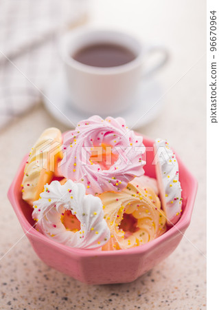 Different colors meringues with sprinkles in pink bowl. Different colors meringues with sprinkles in pink bowl. 96670964
