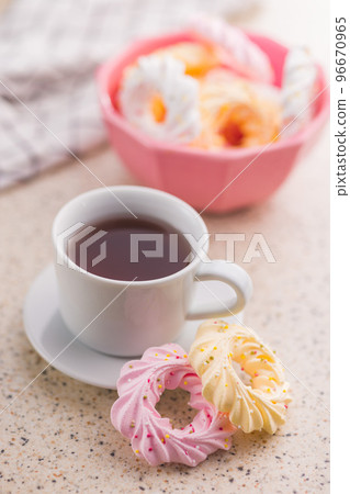 Different colors meringues with sprinkles and tea cup. 96670965