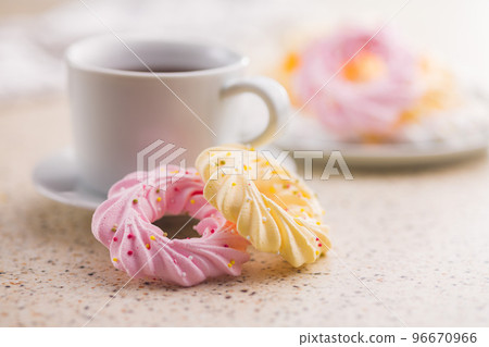 Different colors meringues with sprinkles and tea cup. 96670966