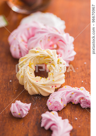 Different colors meringues with sprinkles on wooden table. 96670967