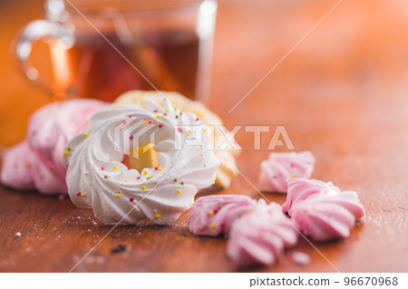 Different colors meringues with sprinkles on wooden table. 96670968
