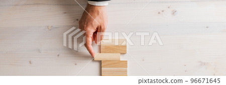 Top view of male hand in a suit pushing a blank wooden peg into a stack of them Top view of male hand in a suit pushing a blank wooden peg into a stack of them 96671645
