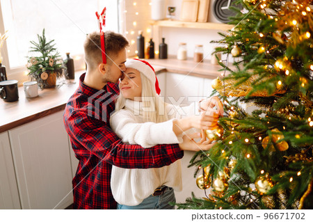 Happy couple decorating christmas tree at home. Smiling Man and Woman together Celebrating Christmas Happy couple decorating christmas tree at home. Smiling Man and Woman together Celebrating Christmas 96671702