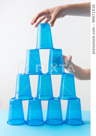 Pyramid of blue plastic cups. Set for party. Children hands 96671816