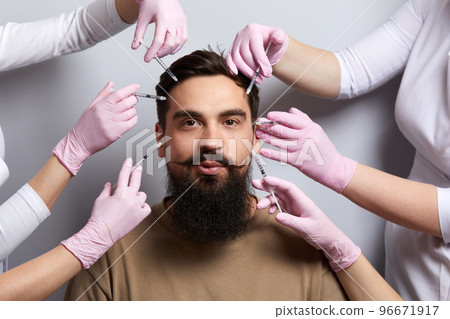 Hands of several doctors holding syringes over male face. Beauty and Cosmetology concept. Cosmetic procedures mesotherapy 96671917