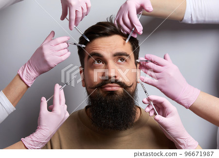 Conceptual beauty and cosmetology image of hands of several doctors holding syringes over male face. Beauty and Cosmetology concept. Cosmetic procedures mesotherapy Conceptual beauty and cosmetology image of hands of several doctors holding syringes over male face. Beauty and Cosmetology concept. Cosmetic procedures mesotherapy 96671987