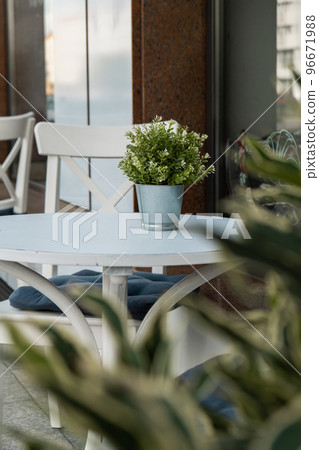 Outdoor table in street cafe. Outdoor empty coffee and restaurant terrace with potted plants tables and chairs in london indie and hipster style. Travel concept Outdoor table in street cafe. Outdoor empty coffee and restaurant terrace with potted plants tables and chairs in london indie and hipster style. Travel concept 96671988