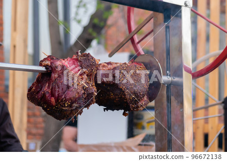 Process of cooking large meat peaces on spit over open fire Process of cooking large meat peaces on spit over open fire 96672138