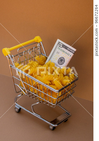 Shopping trolley cart Filled With Pasta with 5 US dollar paper money banknote on Beige background. Copy space for your text. Food and groceries shopping price increase, Rising food cost food crisis 96672264