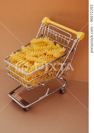 Shopping trolley cart Filled With Pasta on Beige background. Copy space for your text. Food and groceries shopping price increase, Rising food cost food crisis inflation concept. Online shopping, buy 96672265