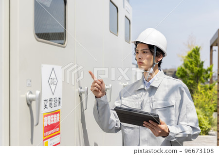Male worker inspecting substation equipment 96673108