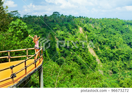 Woman stand at balcony on high cliff with jungle view 96673272