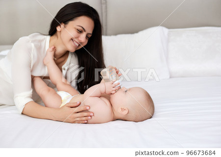 happy mother feeding her newborn baby on the bed 96673684