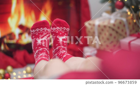 Girl near Christmas gift boxes on background Christmas lights, garlands and fireplace. Woman wraps  96673859