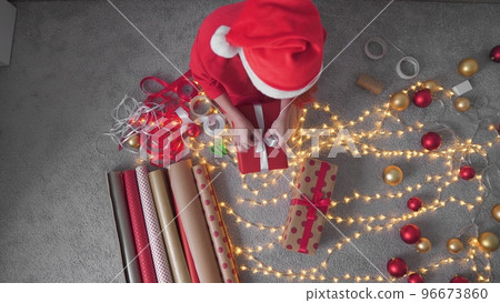 Girl creates New Year's packages with red paper, colored ribbons. A young woman is packing Christmas Girl creates New Year's packages with red paper, colored ribbons. A young woman is packing Christmas 96673860