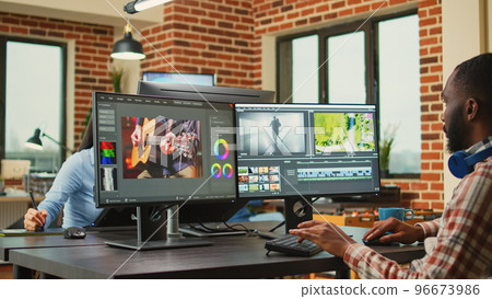 African american freelancer working on video filmmaking at agency workstation, creating professional content. Video editing designer using cinematography software to edit film or movie montage. 96673986