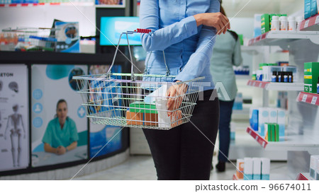 Elderly client choosing vitamins pills from pharmacy shelves, analyzing packages of pharmaceutical products. Asian woman looking to buy prescription treatment or medicine, healthcare shop. 96674011