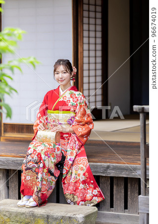 A woman in a kimono sitting on the porch of an old folk house A woman in a kimono sitting on the porch of an old folk house 96674019