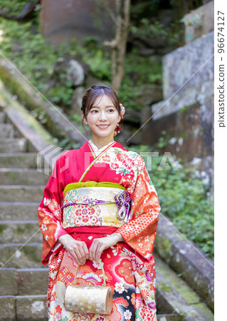 A woman in a kimono standing on the stairs of a shrine 96674127