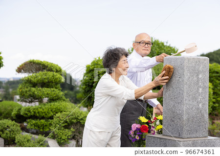 Senior couple cleaning tombstones 96674361