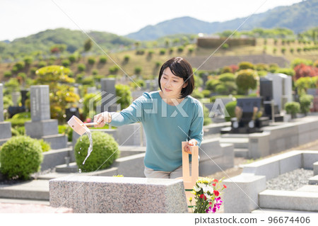 A woman cleaning a tombstone A woman cleaning a tombstone 96674406