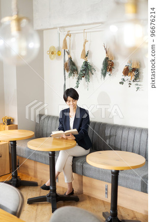 A woman reading a book at a cafe A woman reading a book at a cafe 96676214