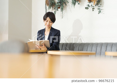 A woman reading a book at a cafe A woman reading a book at a cafe 96676215