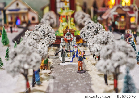 Miniature figures of man in tuxedo and lady in dress, coachman and carriage in miniature winter park. Miniature toy city during winter season. City scene in miniature models Miniature figures of man in tuxedo and lady in dress, coachman and carriage in miniature winter park. Miniature toy city during winter season. City scene in miniature models 96676570
