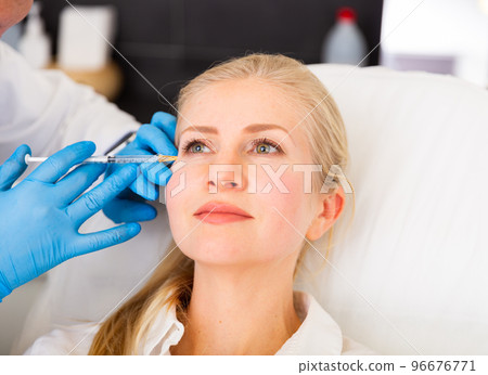 Cosmetologist doing botulotoxin injections for young woman 96676771