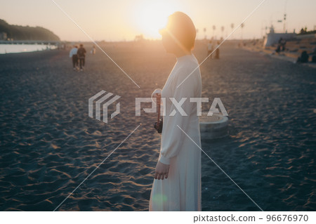 Photo of a woman holding a mirrorless camera at dusk 96676970