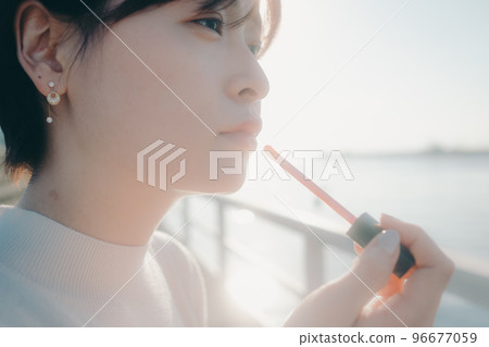 Photo of a young woman applying gloss Photo of a young woman applying gloss 96677059