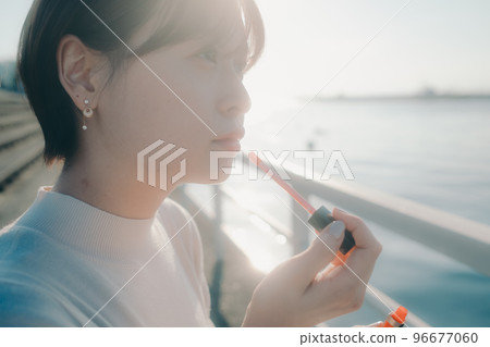 Photo of a young woman applying gloss 96677060
