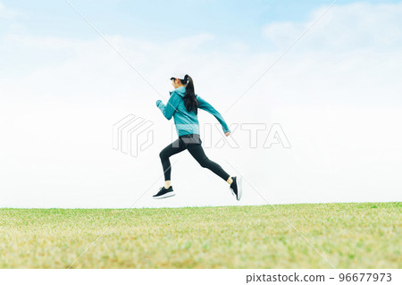 身穿運動服的亞洲女性在草地上跳躍時奔跑 身穿運動服的亞洲女性在草地上跳躍時奔跑 96677973