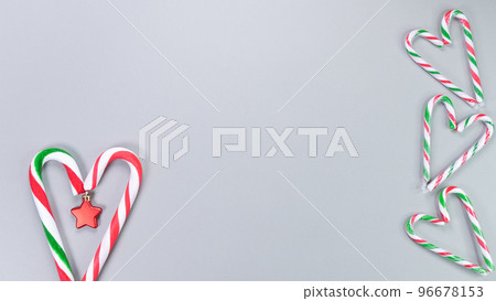 Christmas candy cane, golden and red stars, small and big candies on grey background. Christmas composition. Top view, flat lay Christmas candy cane, golden and red stars, small and big candies on grey background. Christmas composition. Top view, flat lay 96678153
