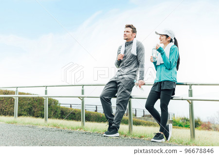 International couple men and women wearing sportswear drinking water to prevent heat stroke after exercising 96678846