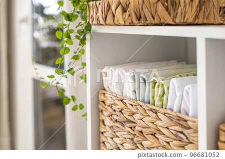 Neatly folded linen cupboard shelves storage at eco friendly straw basket placed closet organizer Neatly folded linen cupboard shelves storage at eco friendly straw basket placed closet organizer 96681052