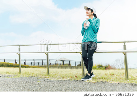 Asian woman drinking water/sport drink during aerobic exercise in the park Asian woman drinking water/sport drink during aerobic exercise in the park 96681359