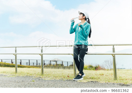 Asian woman drinking mineral water sports drink during aerobic exercise in the park Asian woman drinking mineral water sports drink during aerobic exercise in the park 96681362