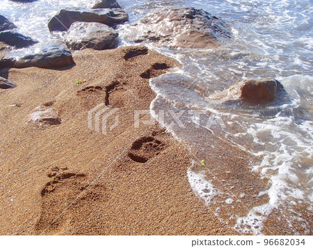 Footprints in the sea sand. A foaming wave rolls ashore. Sea surf. Powerful waves. Storm at sea. Selective focus, shallow depth of field 96682034