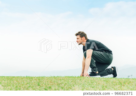 穿著運動服的田徑運動員白人男子在公園裡練習起跑 穿著運動服的田徑運動員白人男子在公園裡練習起跑 96682371