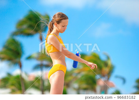 Little girl with bottle of sun cream sitting at tropical beach Little girl with bottle of sun cream sitting at tropical beach 96683182