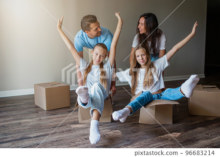 Happy family with two daughters have fun in their new home. Parent with kids enjoy their moving day Happy family with two daughters have fun in their new home. Parent with kids enjoy their moving day 96683214